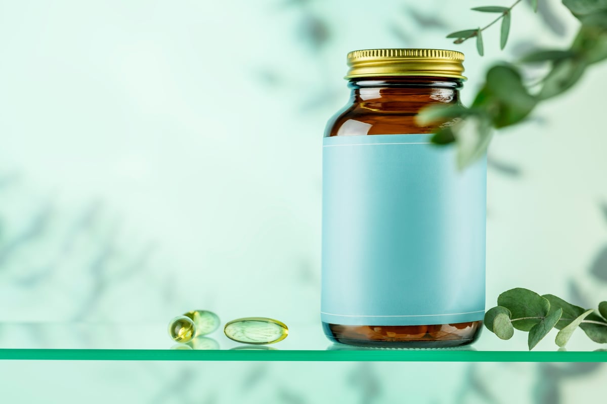 Mockup of natural bio pills or supplements on blue gradient background with eucalyptus leaves.