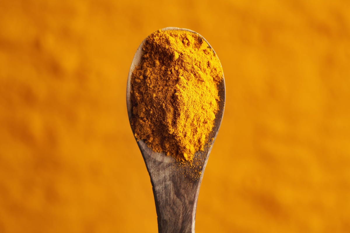 Turmeric root powder on a wooden spoon, top view